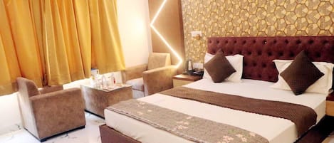 Una habitación de hotel con una cama grande, un sofá, una mesita y una mesita de noche.