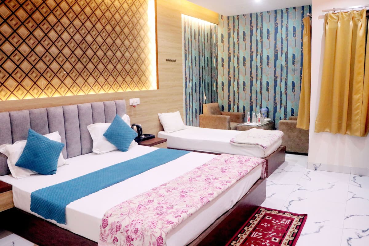 A hotel room with two beds, a sofa, a small table, and a patterned rug.