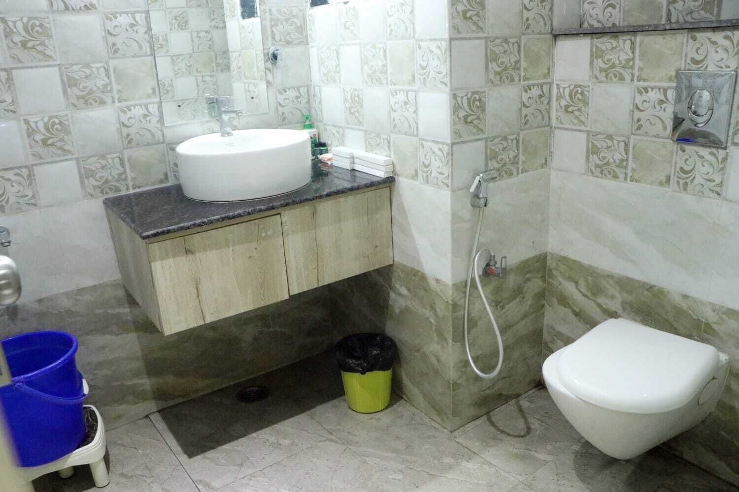 Et badeværelse med vask, toilet og bruser.