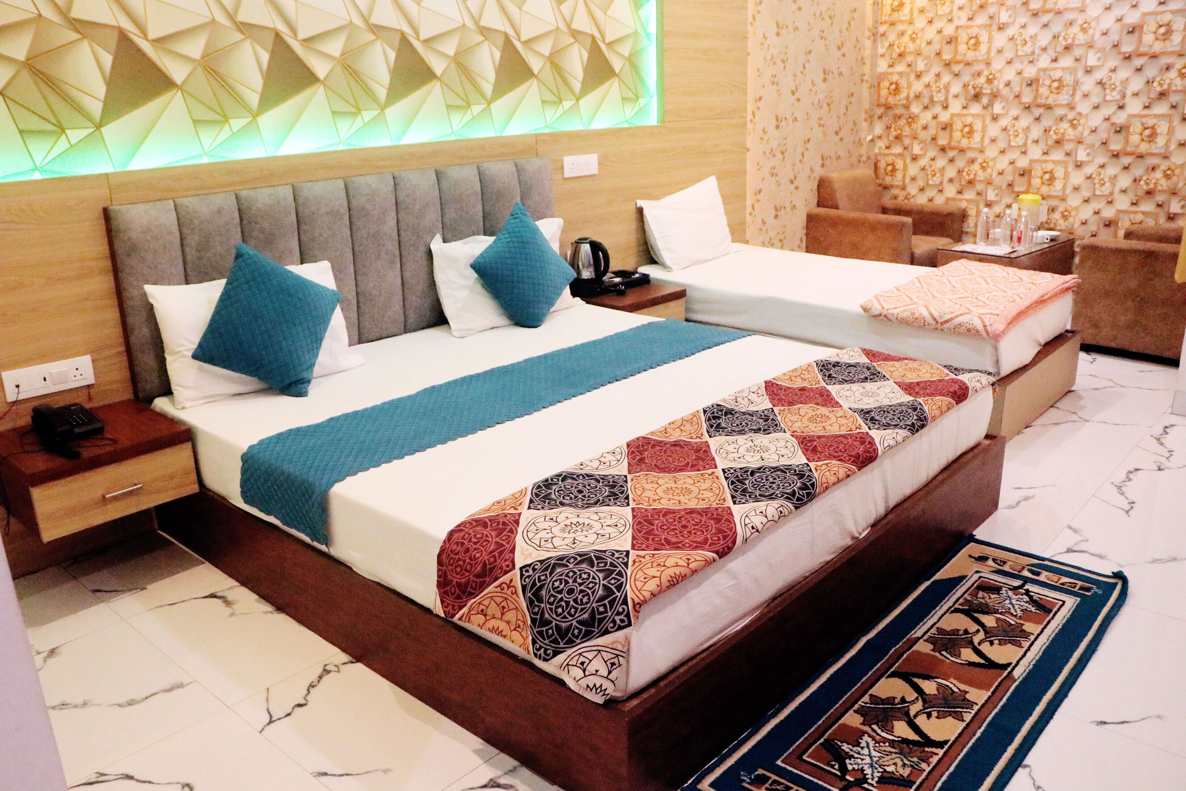 A modern hotel room with a large bed, two bedside tables, a nightstand, and a seating area with a sofa and chairs.