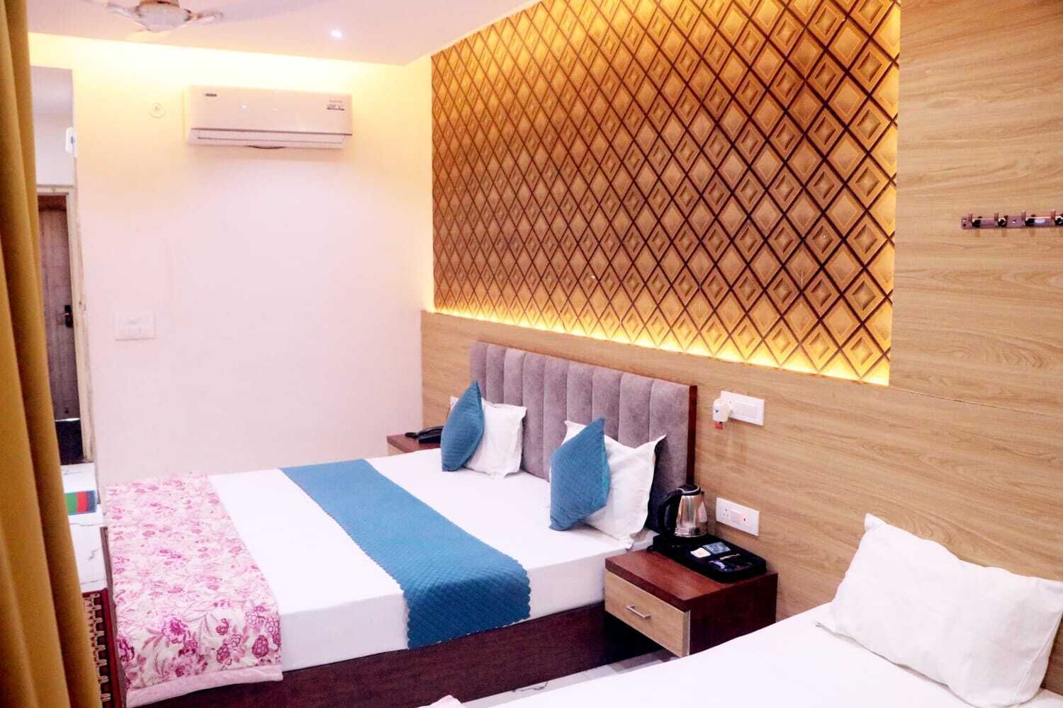 A hotel room with a bed, bedside table, and a wall-mounted air conditioner.