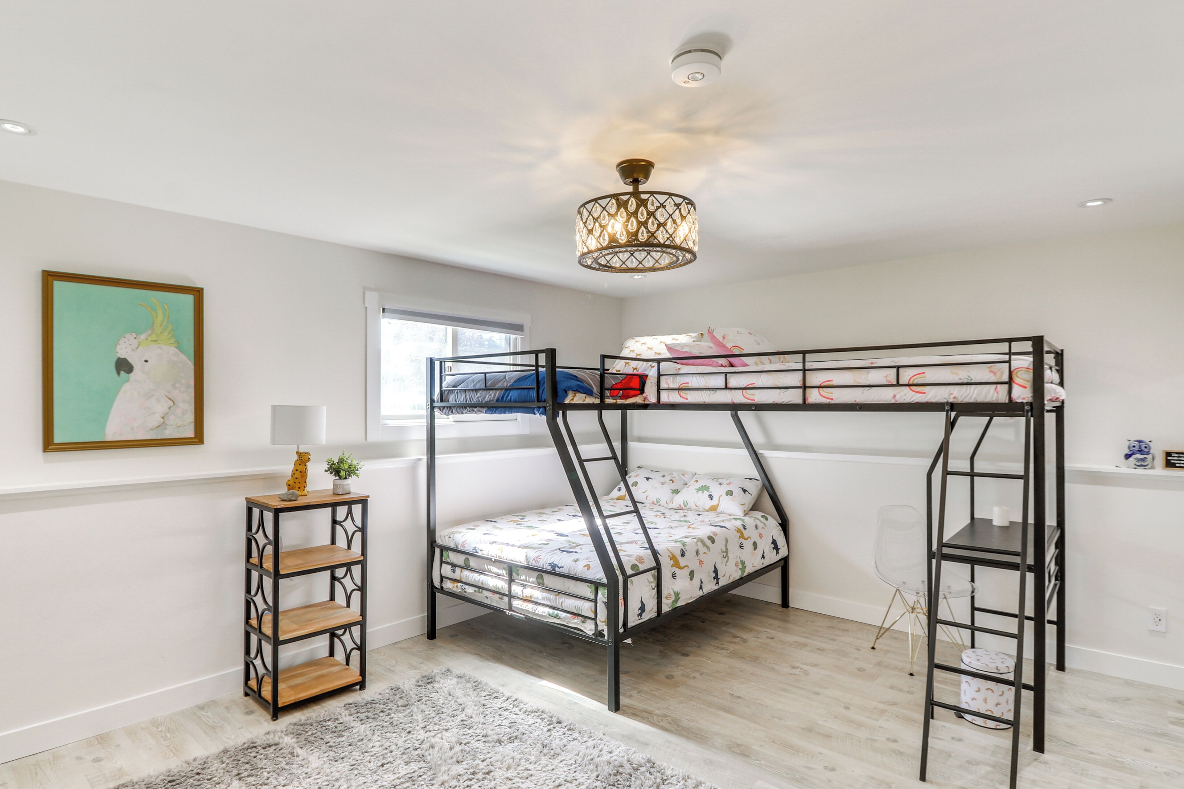 A bunk bed room with a chandelier, a small table, and a framed picture on the wall.