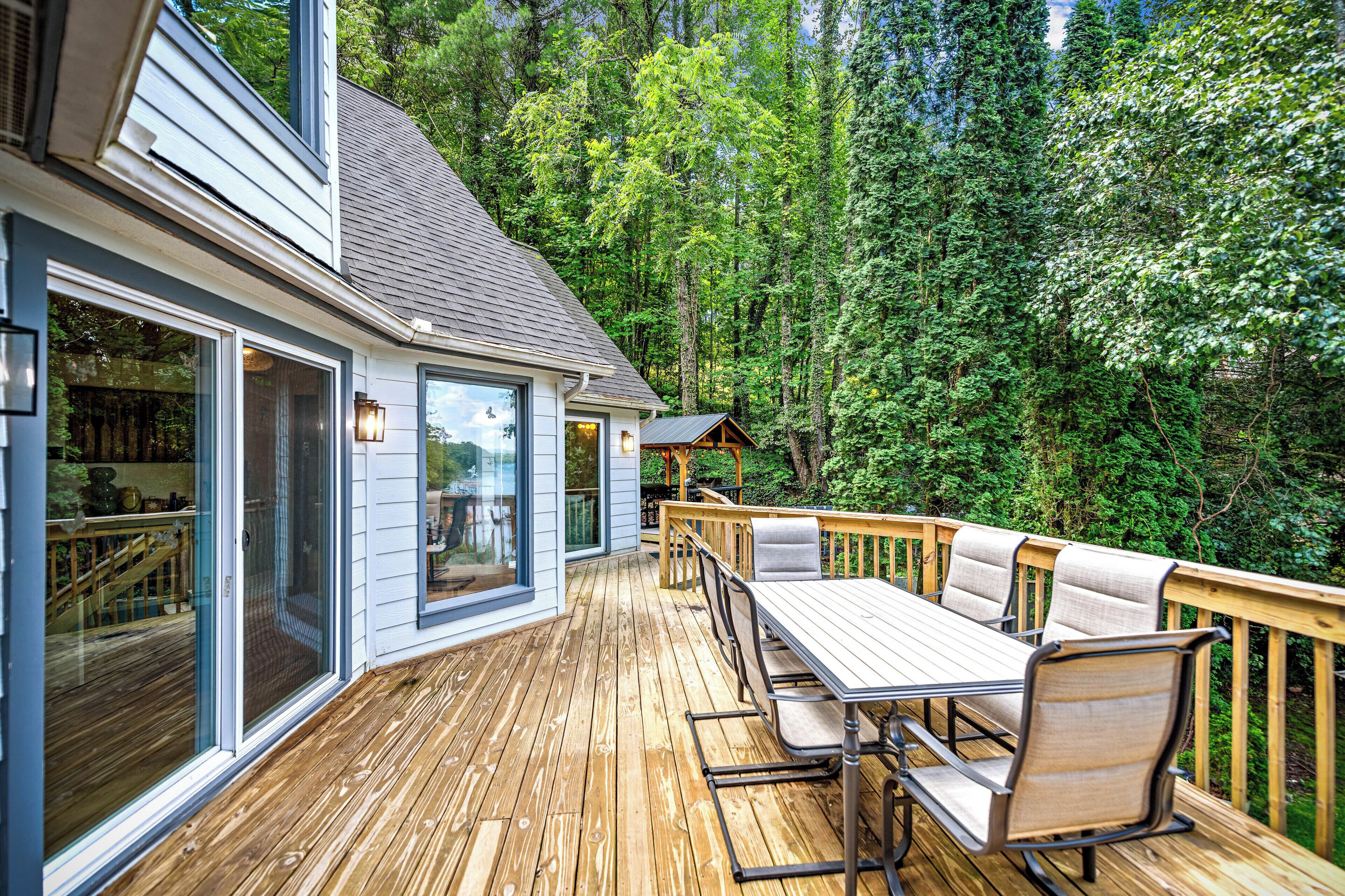 A wooden deck with a table and chairs, surrounded by a forest.