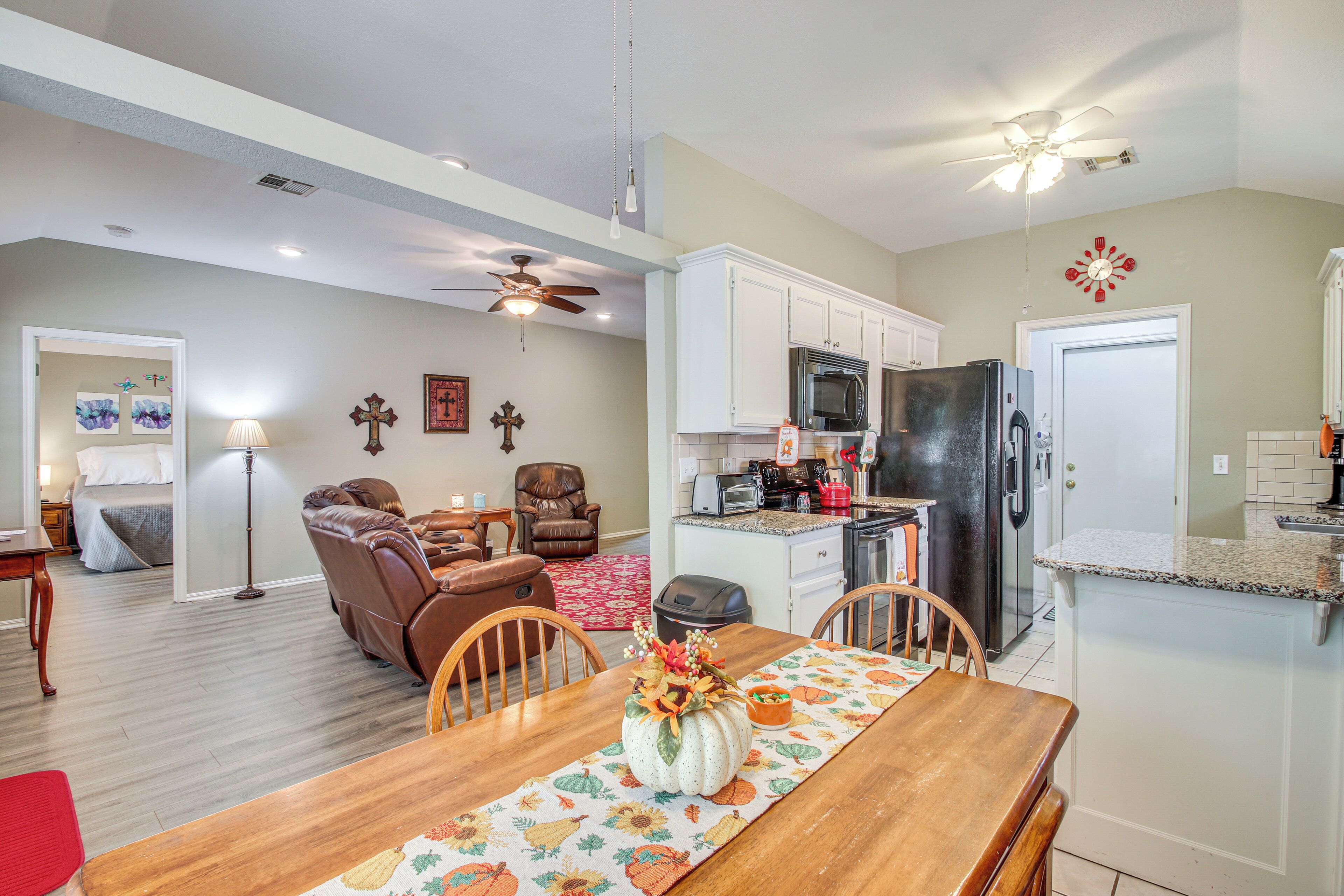 A spacious living room with a fireplace, a dining area with a wooden table, and a kitchen with white cabinets and modern appliances.