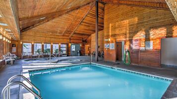 Une piscine intérieure en bois, dotée de chaises longues et d’un espace sauna.