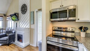A modern kitchen with stainless steel appliances, a fireplace, and a dining area with a leather chair. - 2 Mi to Ober Mountain: Gatlinburg Condo w/ Balcony (Gatlinburg)