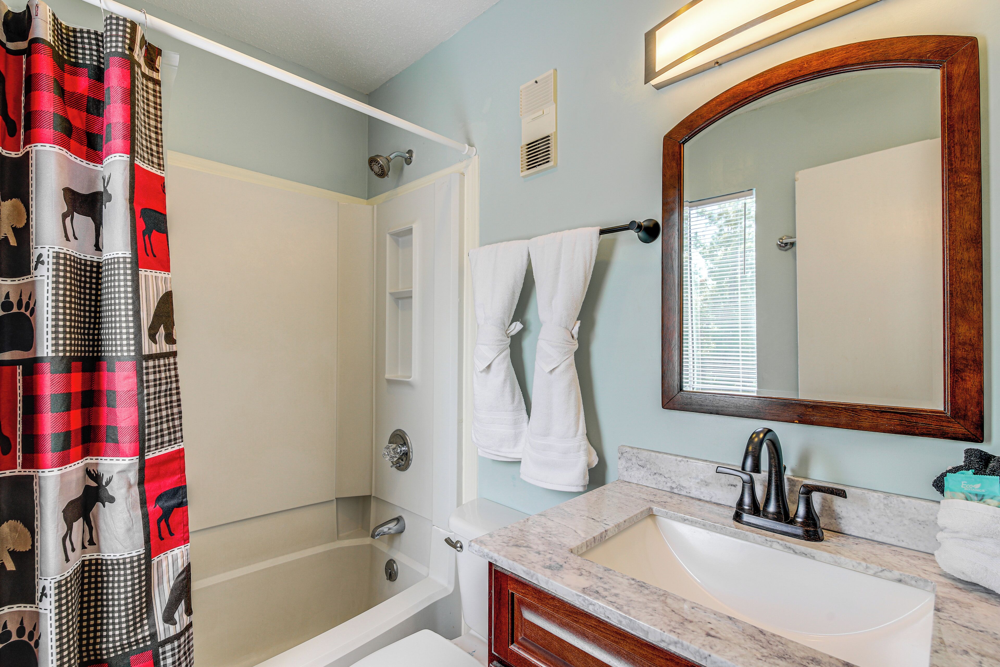 A bathroom with a shower, a sink, a mirror, and a towel rack.