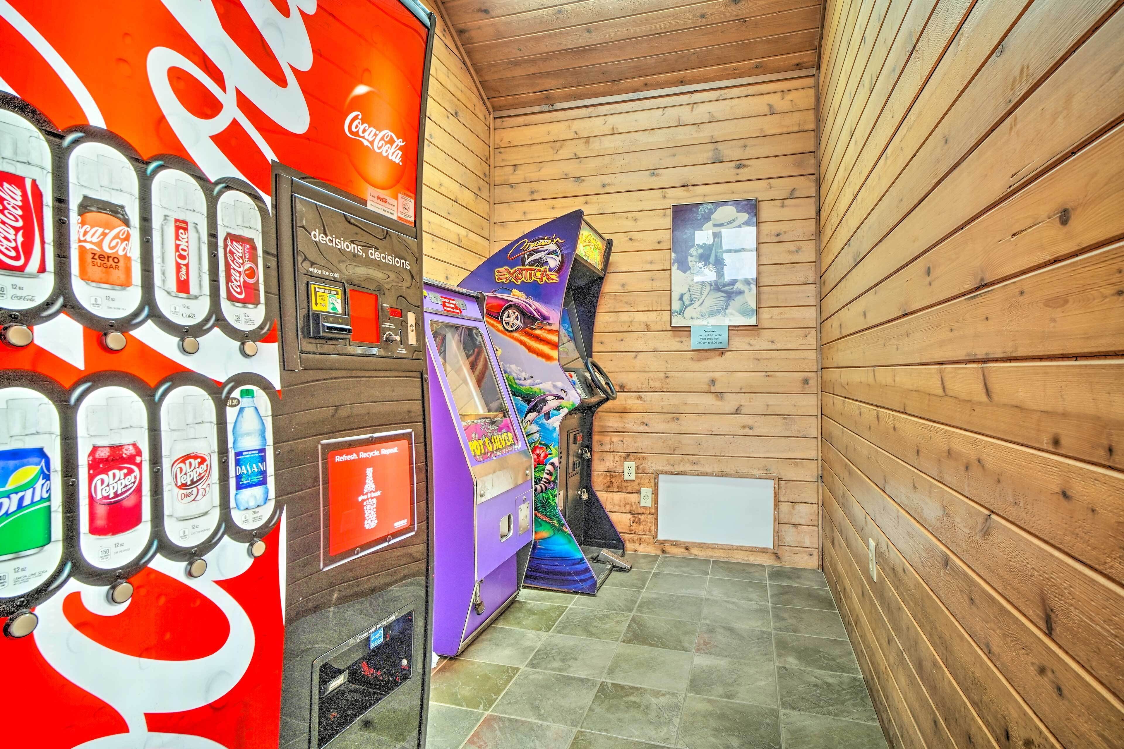Ein Automatenbereich mit verschiedenen Getränkeoptionen, einer Coca-Cola-Werbung und einem Spielgerät.