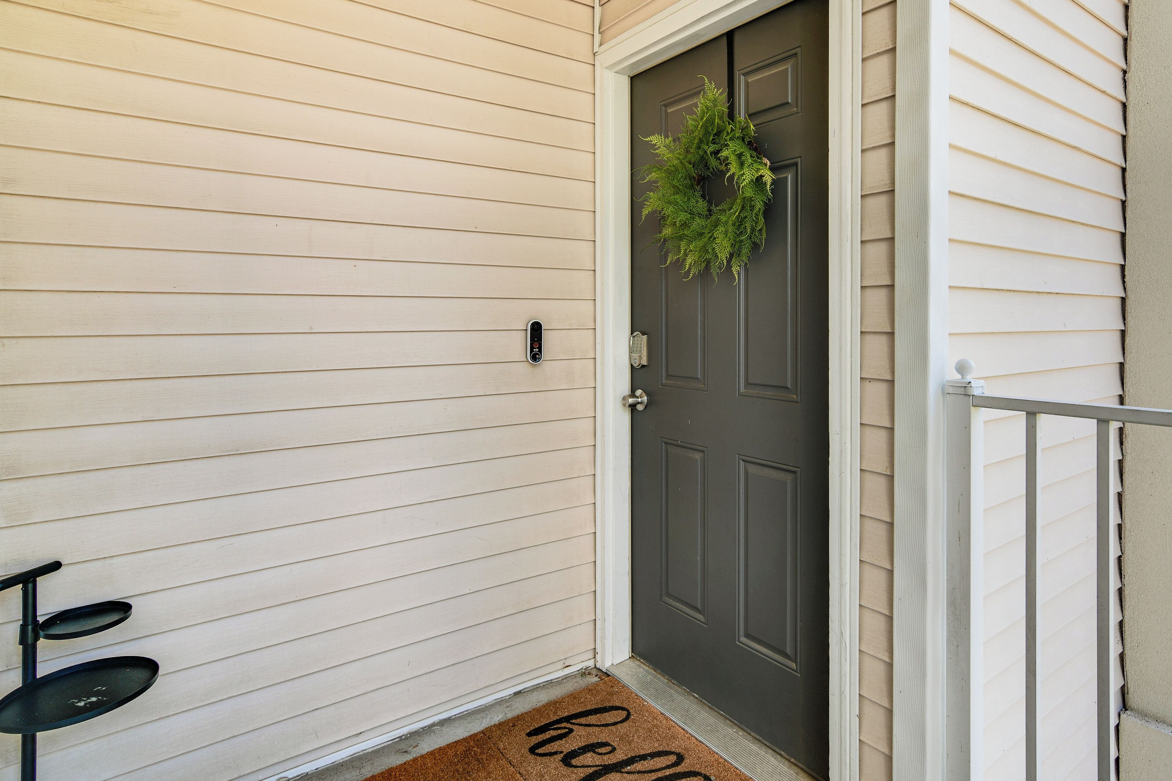 A front door with a dark-colored door, a wreath, and a doormat with the word "hello".