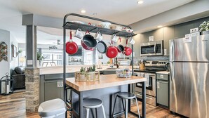 A modern kitchen with a central island, stainless steel appliances, and hanging pots. - Condo w/ Pool ~ 2 Mi to Table Rock Lake! (Branson)