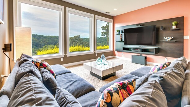 Una sala de estar moderna con un gran ventanal, un televisor de pantalla plana y un sofá con cojines de colores.