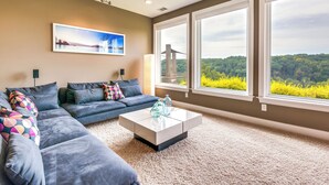 Una sala de estar moderna con un sofá modular, una mesa de centro blanca y ventanas amplias que ofrecen vistas a un puente y zonas verdes.