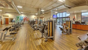 Une salle de sport équipée de matériel d’exercice, dotée d’un plancher en bois et ornée d’une fresque murale.