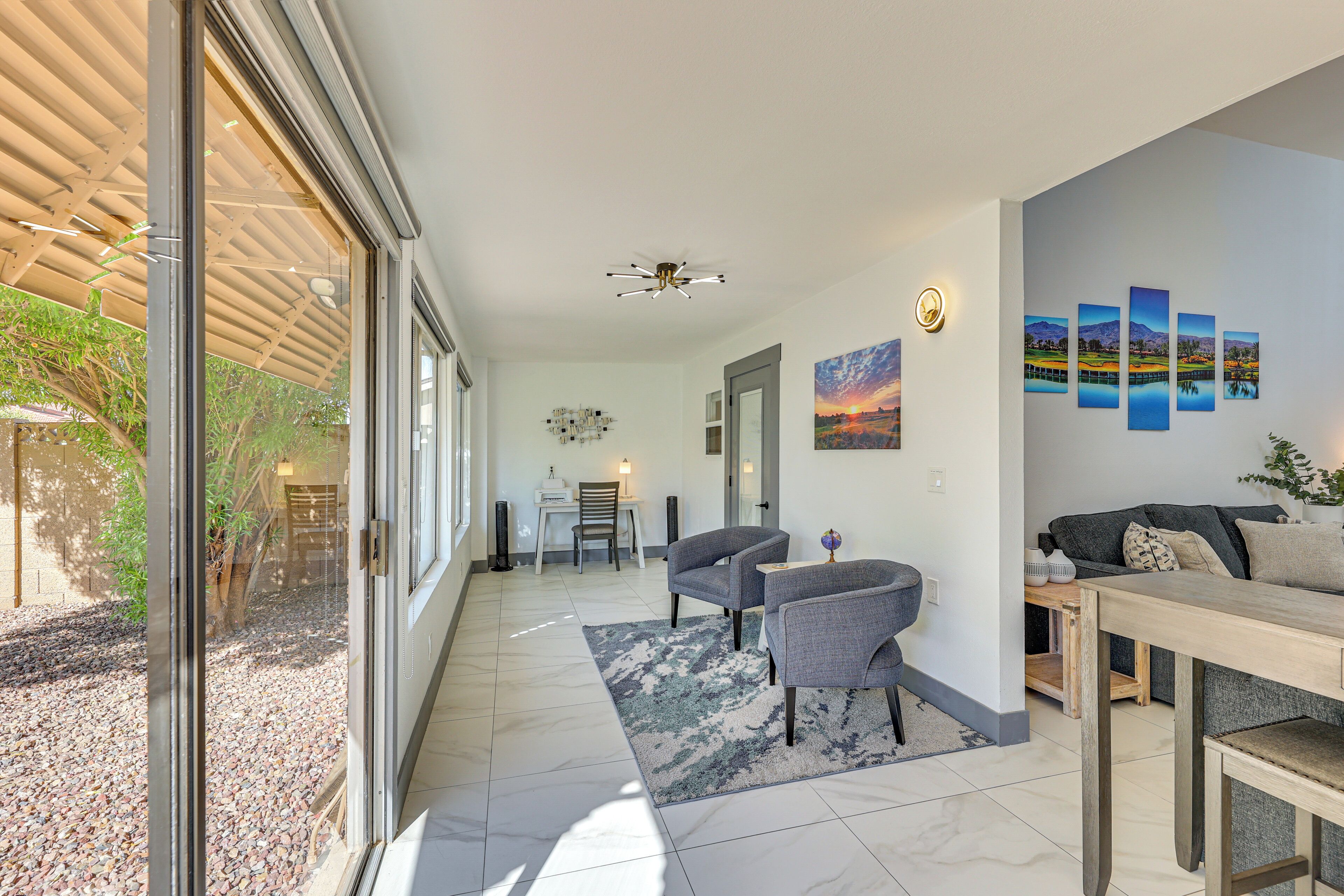 A spacious living area with a large window, a ceiling fan, and a dining table with chairs.