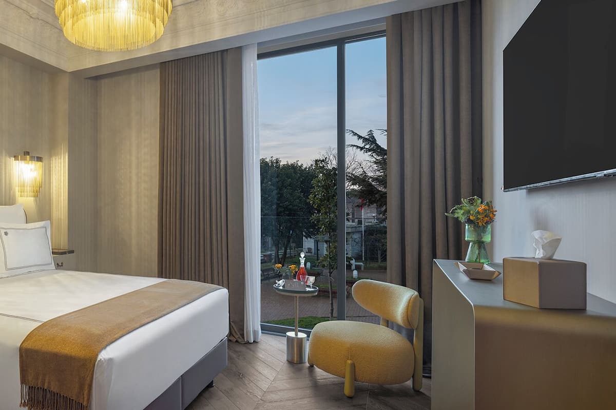 Une chambre d’hôtel moderne dotée d’un grand lit, d’un coin salon et offrant une vue sur l’extérieur.