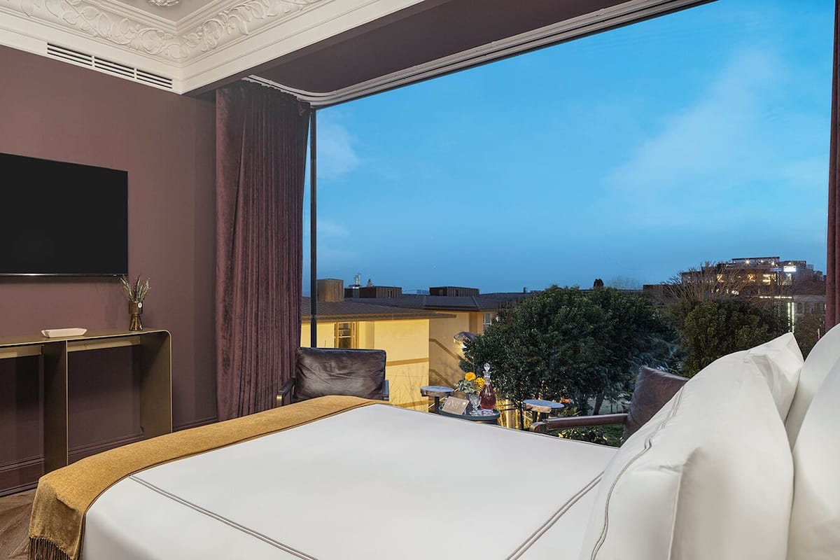 Une chambre d’hôtel avec un grand lit, un bureau, une télévision et une vue sur la ville.