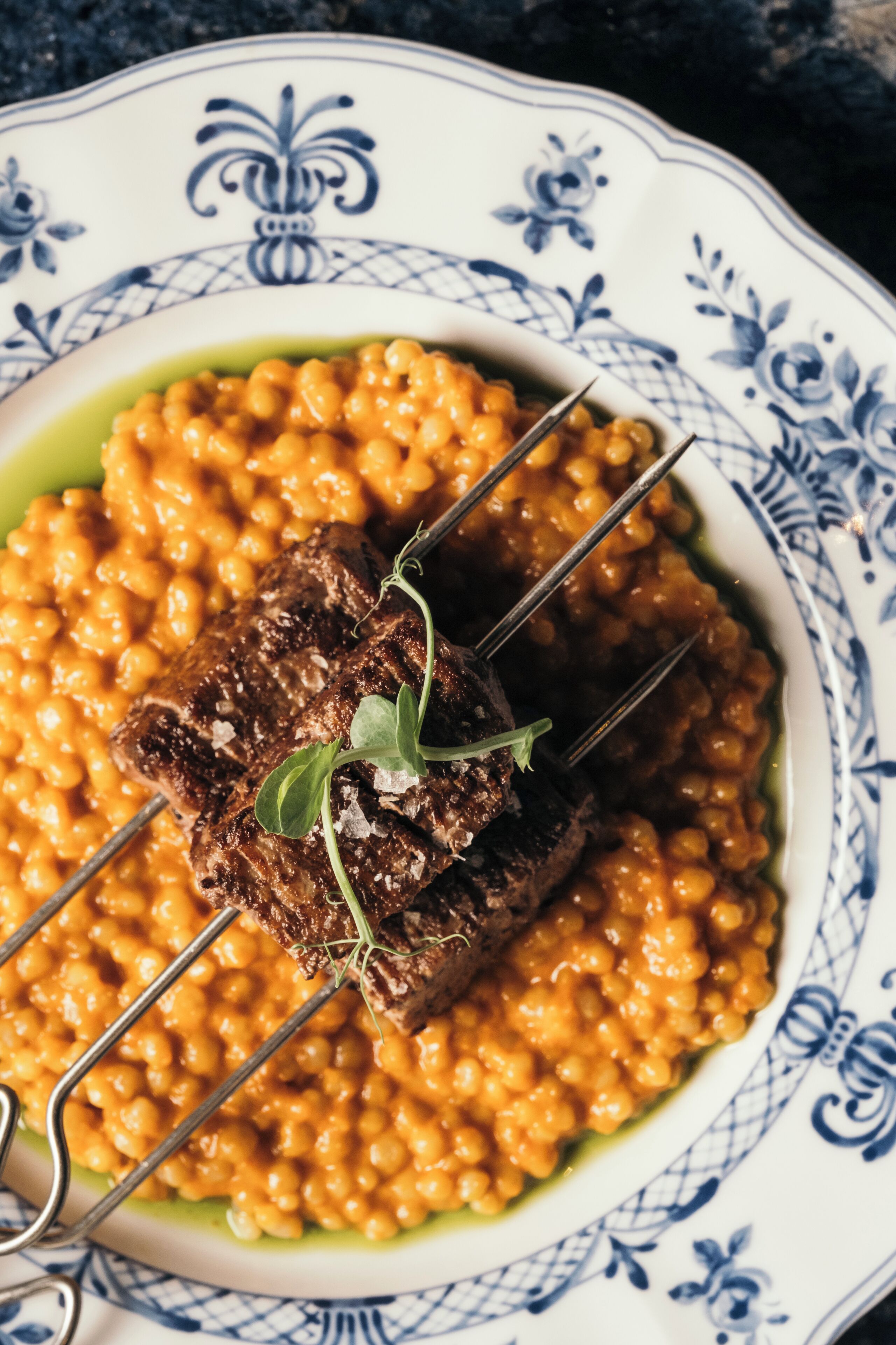 A plate of food with a skewer of meat and beans.