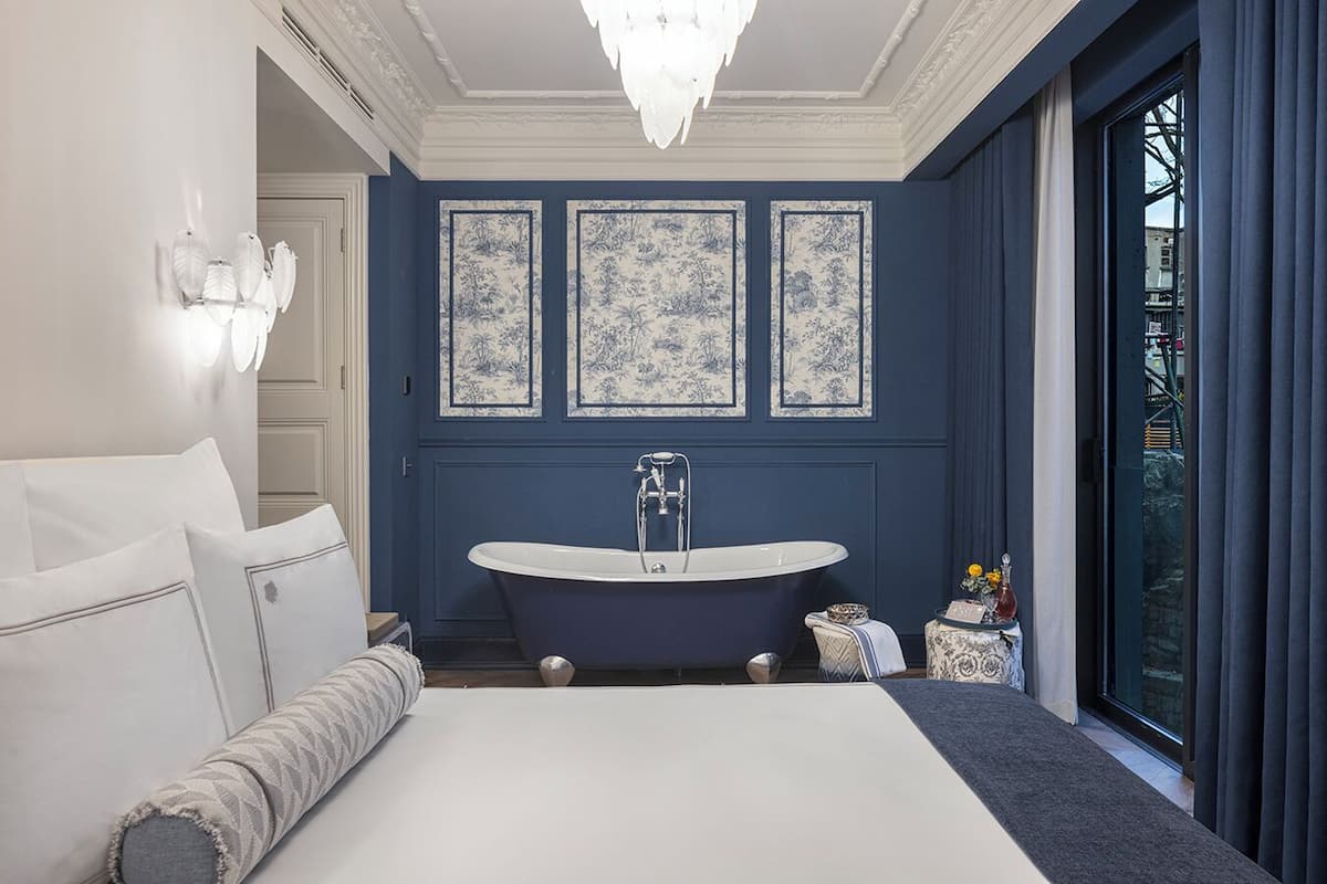 Une salle de bain moderne avec une baignoire sur pieds, un grand miroir et trois panneaux décoratifs floraux encadrés.