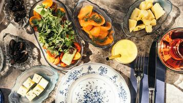 A table set with various dishes, including a salad, cheese, and meats, on a marble table.
