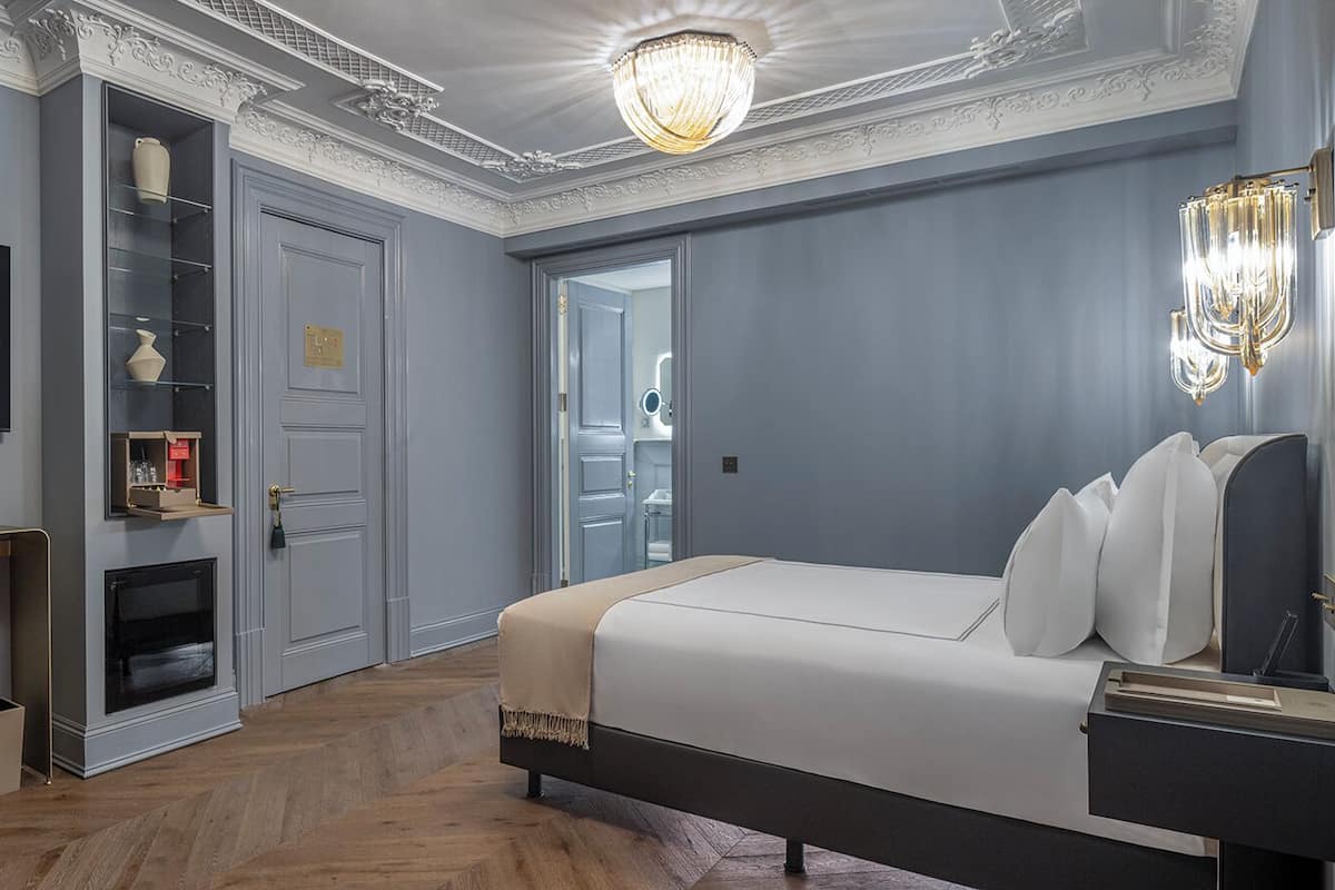 Une chambre d’hôtel moderne dotée d’un grand lit, d’une télévision, d’un minibar et d’un luminaire décoratif au plafond.