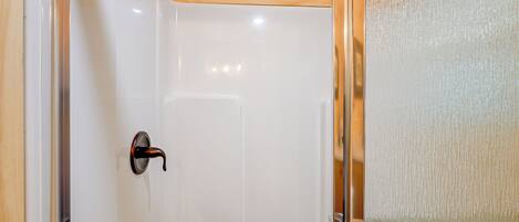 A shower with a wooden ceiling and a glass door.