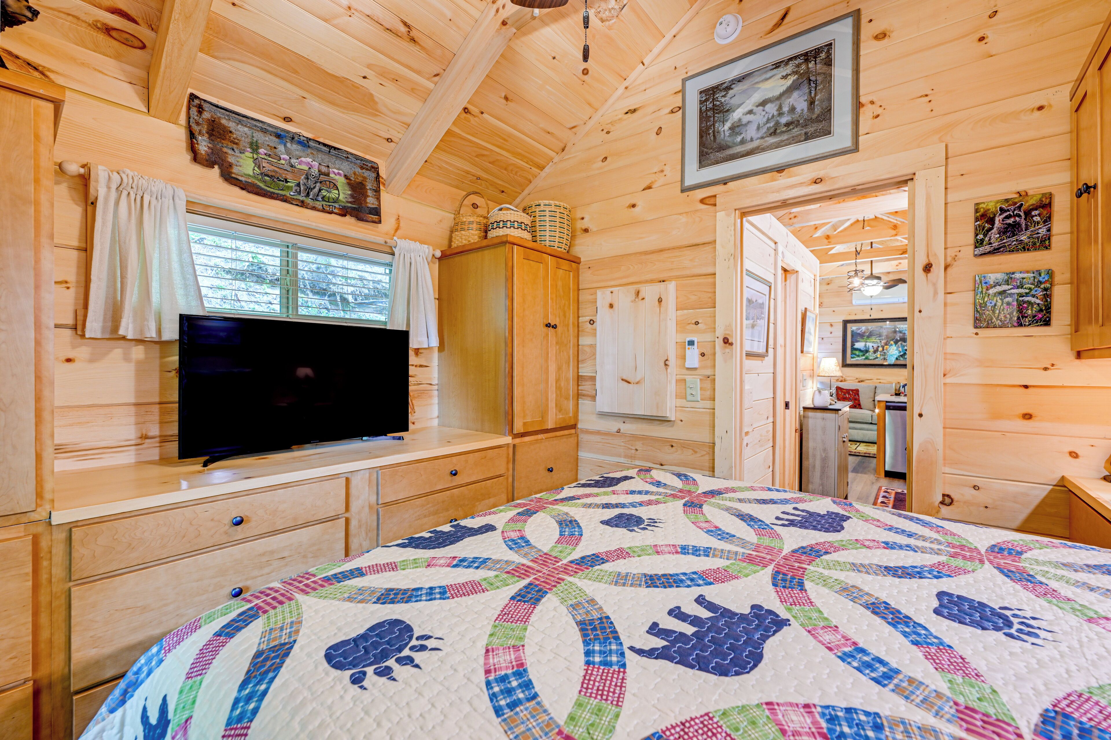 Une chambre dans une cabane en bois, avec un lit, une commode, une télévision et une courtepointe.