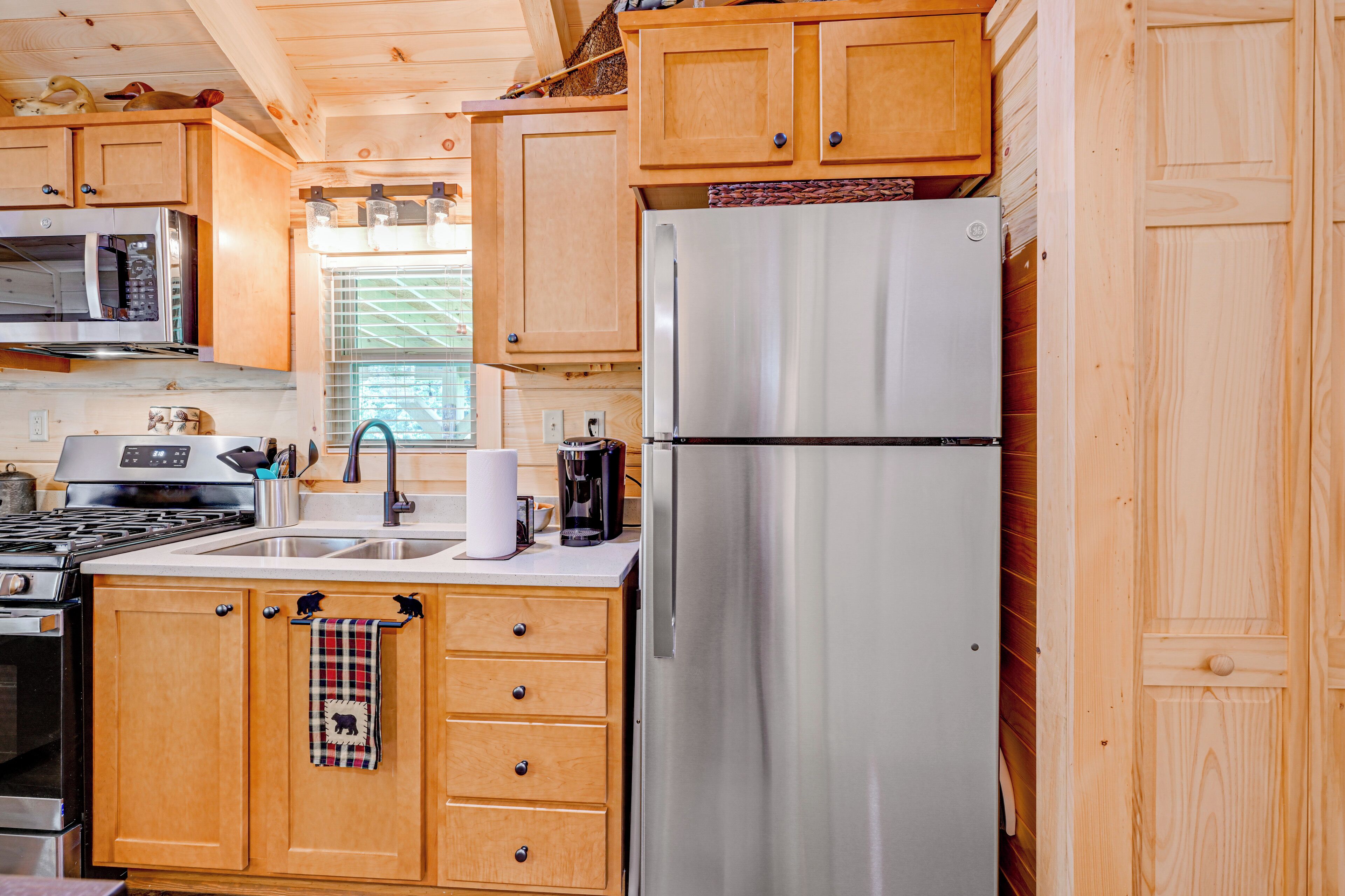 A compact kitchen with wooden cabinets, stainless steel appliances, and a window providing natural light.