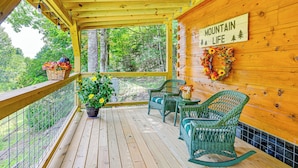 A wooden deck with wicker chairs and a table, surrounded by a metal railing. A sign on the wall reads "MOUNTAIN LIFE".