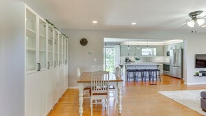 A modern kitchen with white cabinets, a wooden dining table, and a bar area. - Wooster Family Home w/ Yard & Fire Pit! (Wooster)