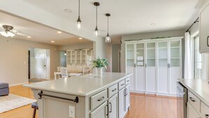 A modern kitchen with white cabinetry, a central island, pendant lighting, and a view into the dining area. - Wooster Family Home w/ Yard & Fire Pit! (Wooster)