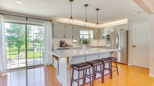 A modern kitchen with a large island, bar stools, and a view of the outdoors. - Wooster Family Home w/ Yard & Fire Pit! (Wooster)