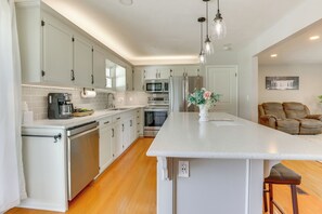 A modern kitchen with white cabinetry, a central island, and stainless steel appliances.