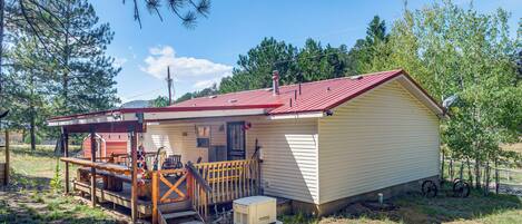 A single-story house with a red roof, a porch, and a small deck.