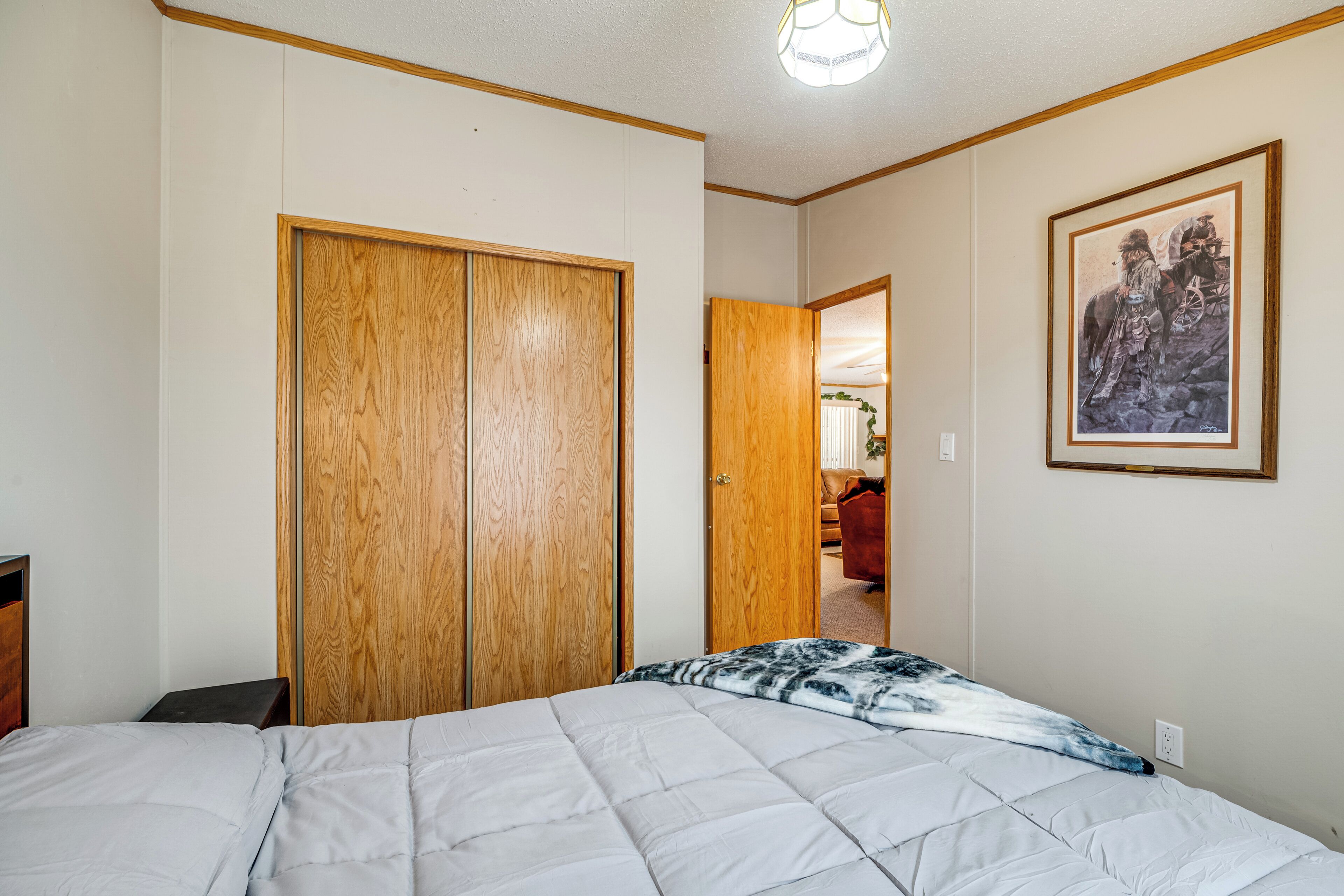 Ein Schlafzimmer mit einem Bett, einem Holzschrank und einem gerahmten Bild an der Wand.