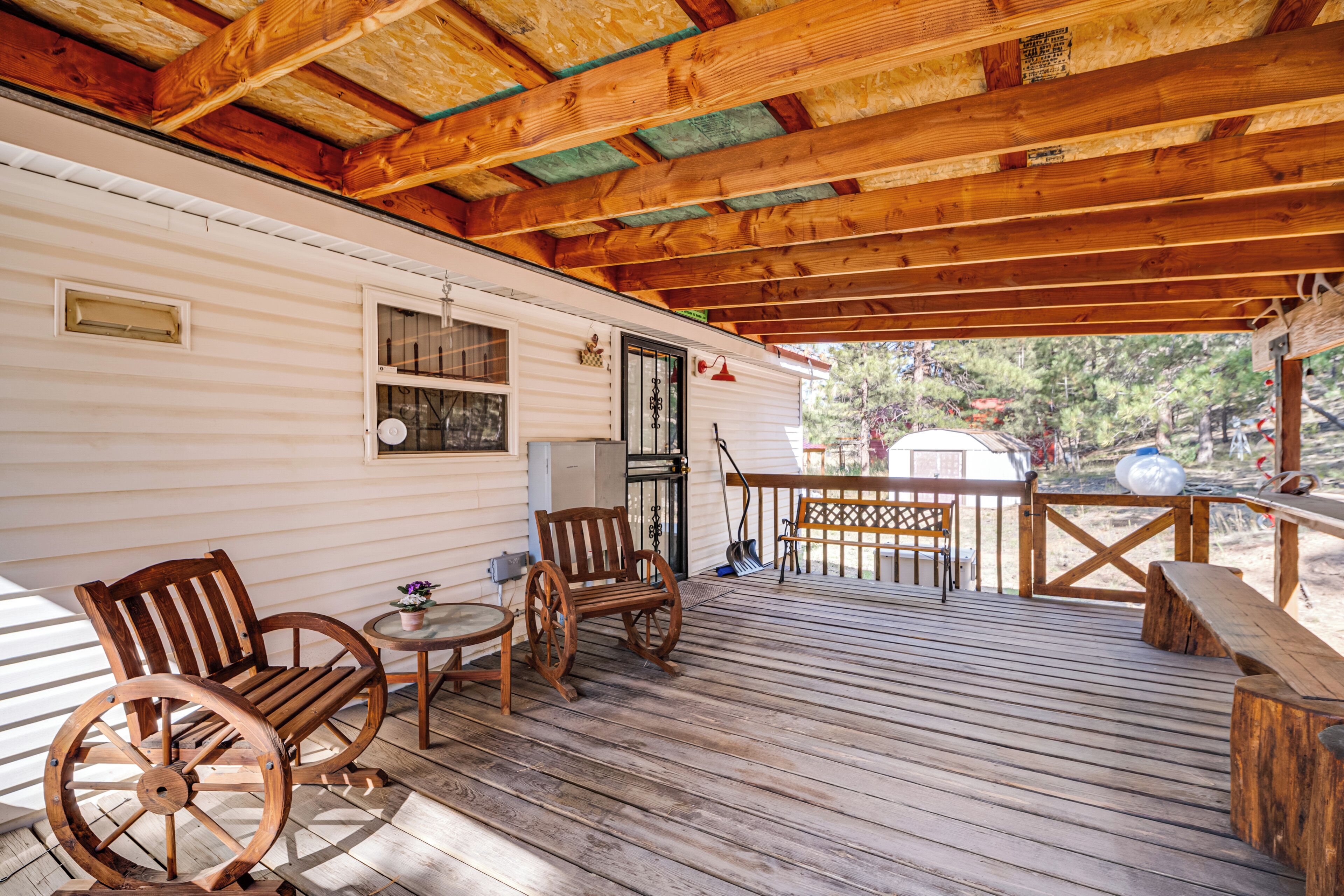 A wooden deck with a covered area, a small table, and two wooden chairs.
