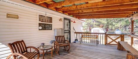 A wooden deck with a covered area, a small table, and two wooden chairs.