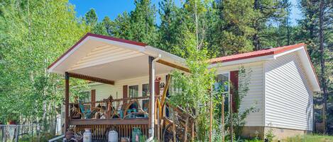 Une cabane dotée d’une véranda, d’une terrasse en bois et d’un petit escalier menant à l’entrée.