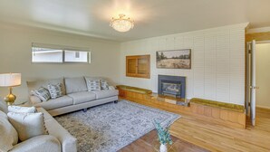 A living room with a sofa, a fireplace, a chandelier, and a window. - Walk to Downtown: Brigham City Family Home (Brigham City)
