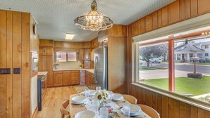 A wooden interior with a dining table set for six, a refrigerator, and a window with a view of a street and houses. - Walk to Downtown: Brigham City Family Home (Brigham City)