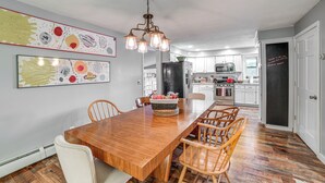 A dining area with a wooden table and chairs, a chandelier, and artwork on the walls. - Home w/ Private Dock Near Colgate University (Hamilton)