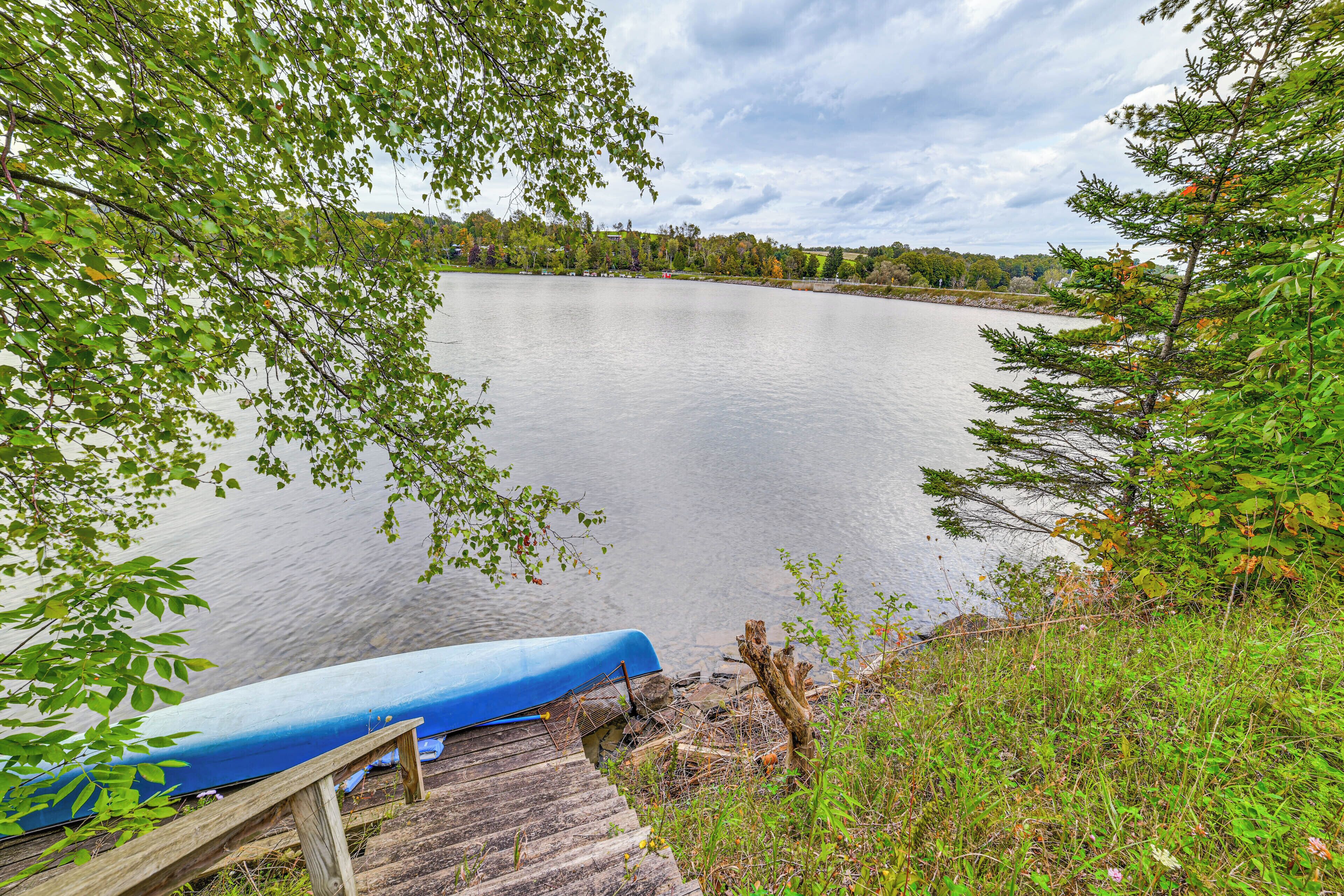 A calm lake with a wooden dock and a blue canoe.