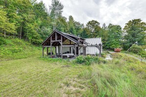 A rustic cabin with a wooden structure, a porch, and a large window. - Home w/ Private Dock Near Colgate University (Hamilton)