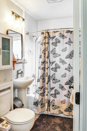 A bathroom with a toilet, sink, and shower curtain with a butterfly pattern.