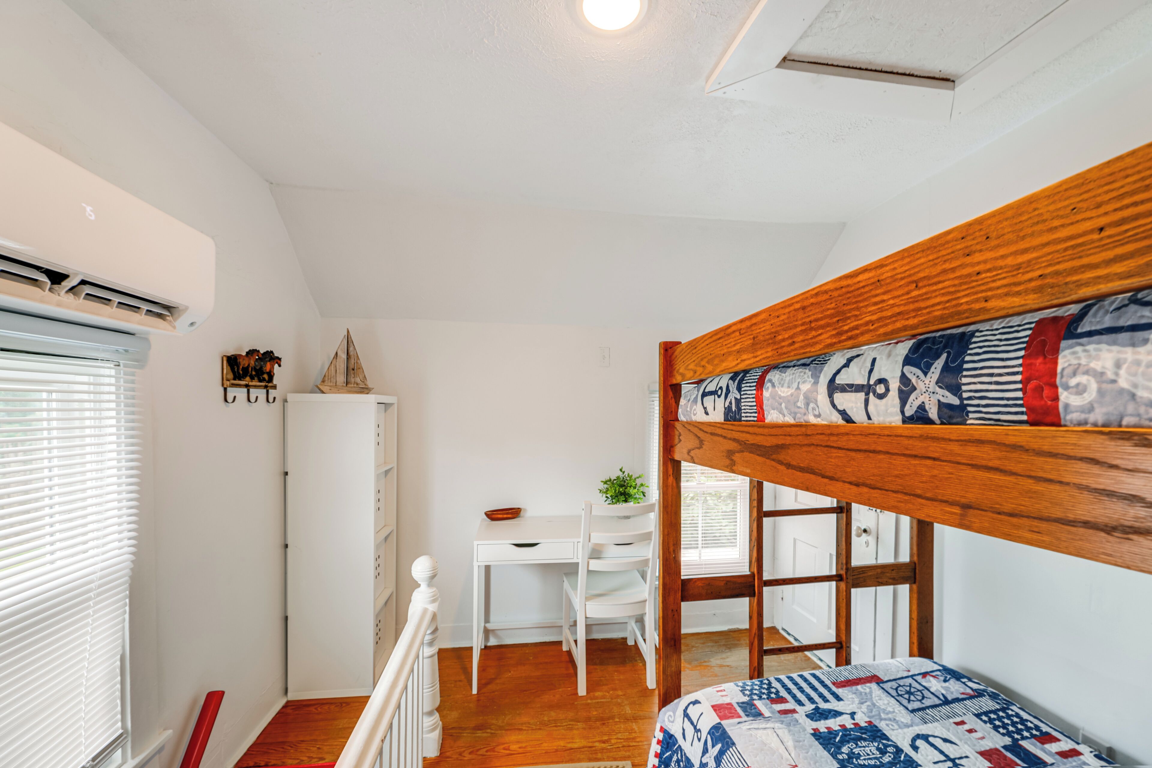 Une chambre avec un lit superposé, un bureau, une chaise et une petite table.