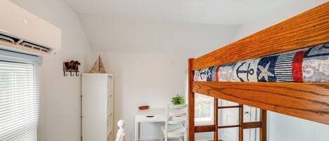 Une chambre avec un lit superposé, un bureau, une chaise et une petite table.