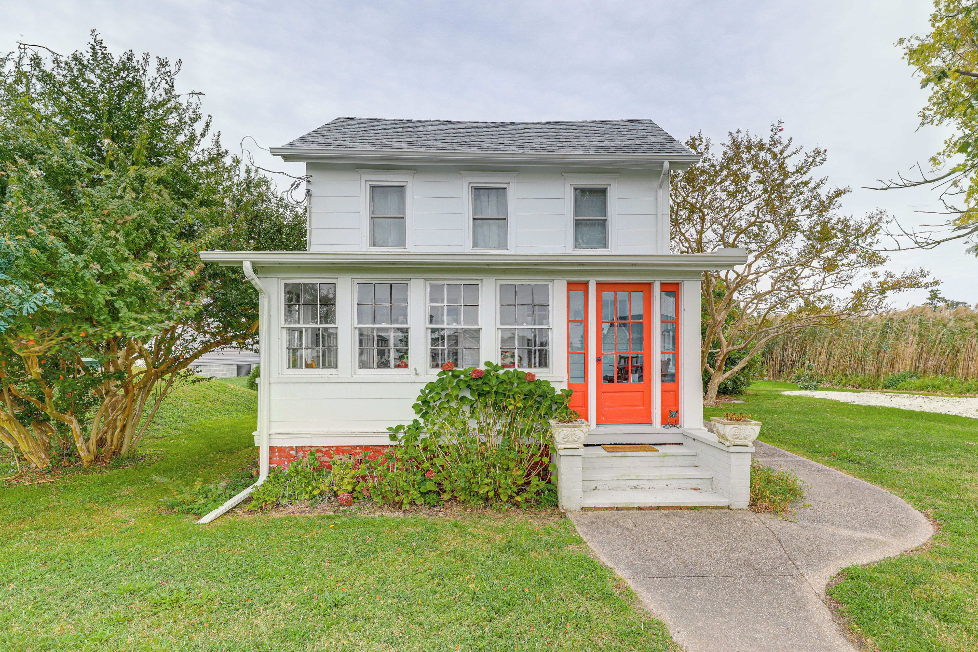 A two-story house with a red door and white exterior.