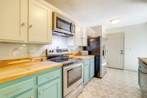 A kitchen with teal cabinets, a stainless steel stove, a microwave, a toaster, and a refrigerator. - Home w/ Trail Access & Fire Pit in Bella Vista! (Bella Vista)