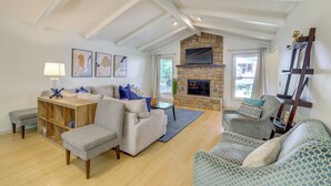 A spacious living room with a high ceiling, a stone fireplace, and a large window. - Home w/ Trail Access & Fire Pit in Bella Vista! (Bella Vista)