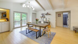 A spacious dining area with a wooden table, benches, and a blue rug. There are white walls, a ceiling fan, and a view of the outdoors through large sliding doors. - Home w/ Trail Access & Fire Pit in Bella Vista! (Bella Vista)