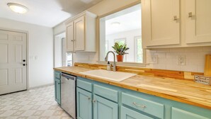 A kitchen with light blue cabinets, a wooden countertop, and a window above the sink. - Home w/ Trail Access & Fire Pit in Bella Vista! (Bella Vista)